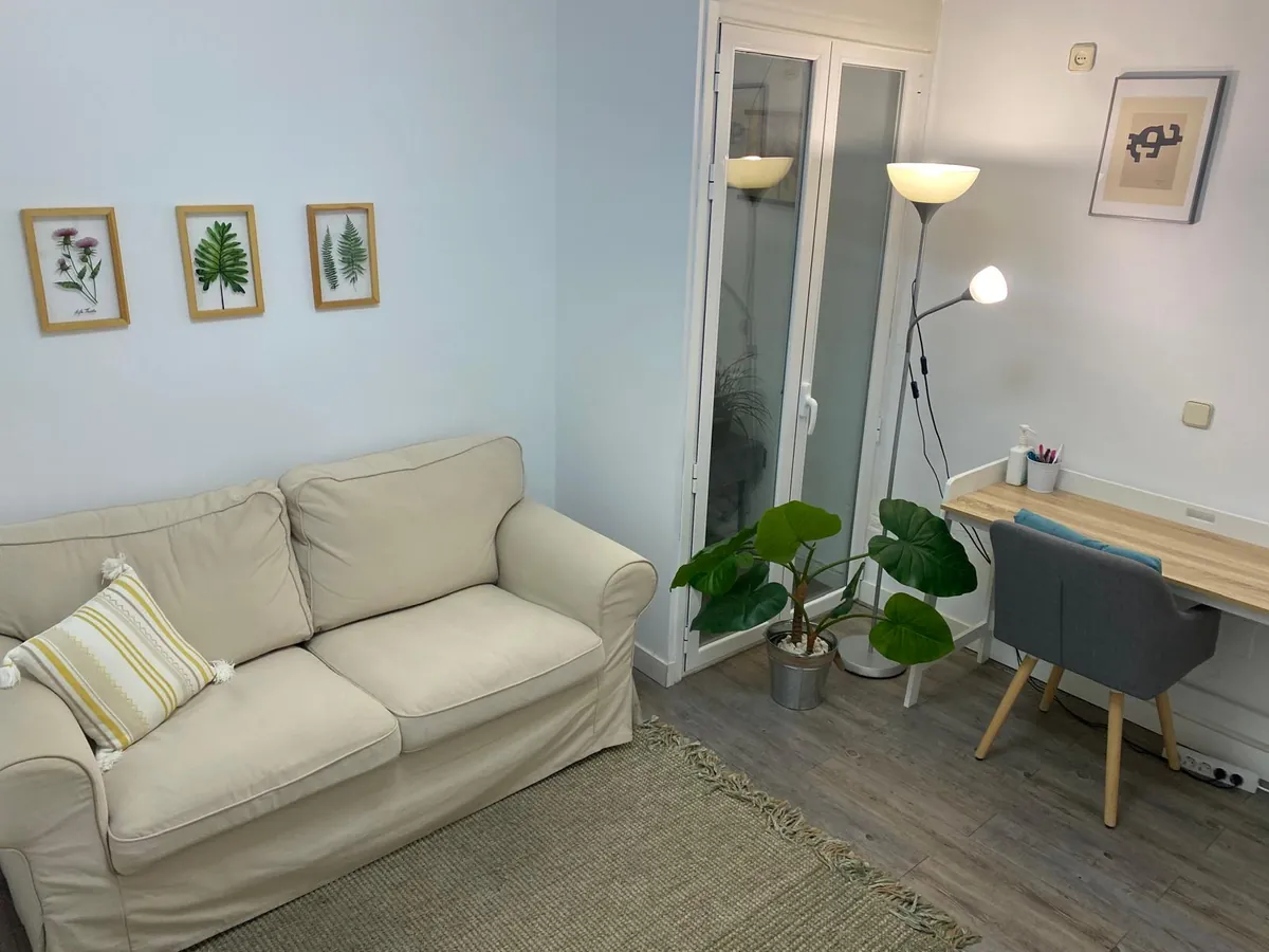 Consulta en Calle Orense, 51, con sofá beige, plantas y láminas botánicas